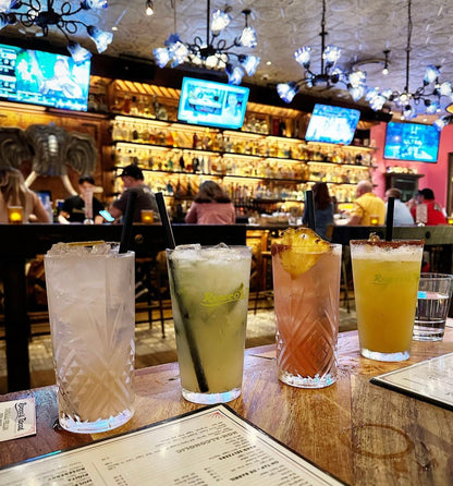 Four cocktail drinks featuring a natural StrawFish straw inside a bar